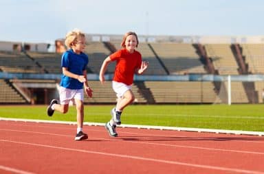 Image of two children running on a track.