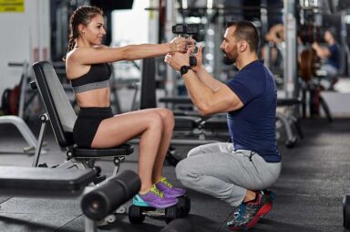 Personal trainer assisting young woman in the gym
