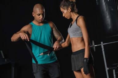 African american male trainer wrapping female boxer