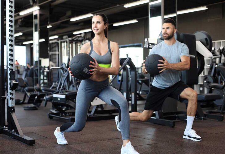 Attractive couple doing fitness with medcine ball at gym