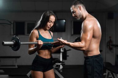 Man instructor and woman train in the gym, lifting dumbbells