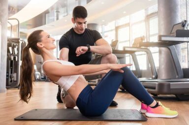 Personal trainer timing young fit woman during isometric exercis