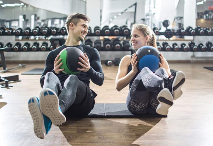 Fit couple doing abdominal exercise with fitness balls