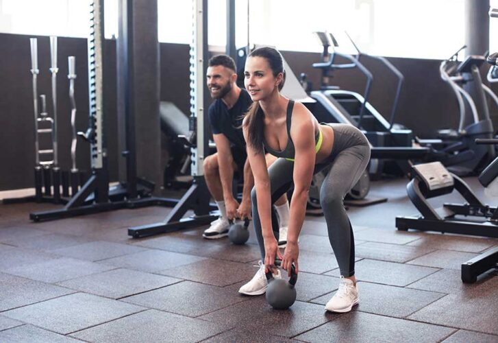 Fit and muscular couple focused on lifting a dumbbell