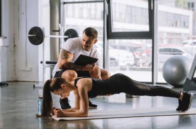 Male personal trainer with clipboard and young athletic