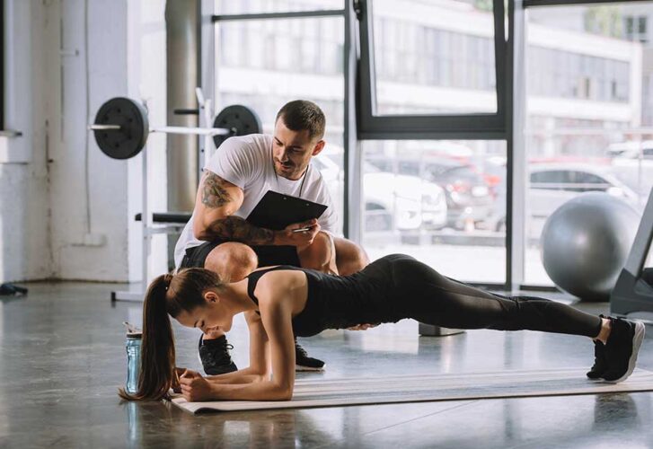 Male personal trainer with clipboard and young athletic