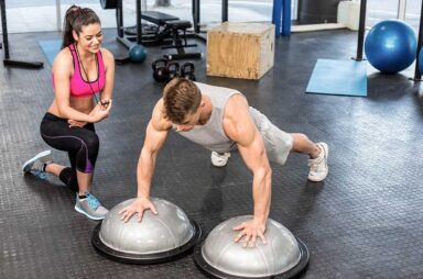 Man working out helped by trainer woman