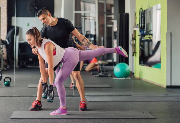 Young woman with personal trainer in the gym