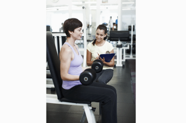 Personal trainer, woman and dumbbell at gym