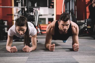 Attractive trainer doing plank exercise together