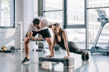 Male personal trainer helping sportswoman