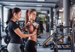 Female personal trainer helping woman doing exercises